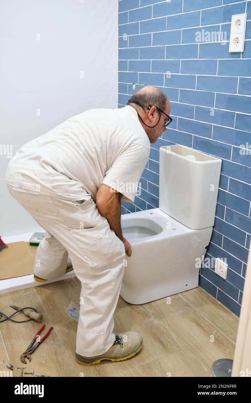 Senior plumber installer installing toilet Stock Photo Alamy