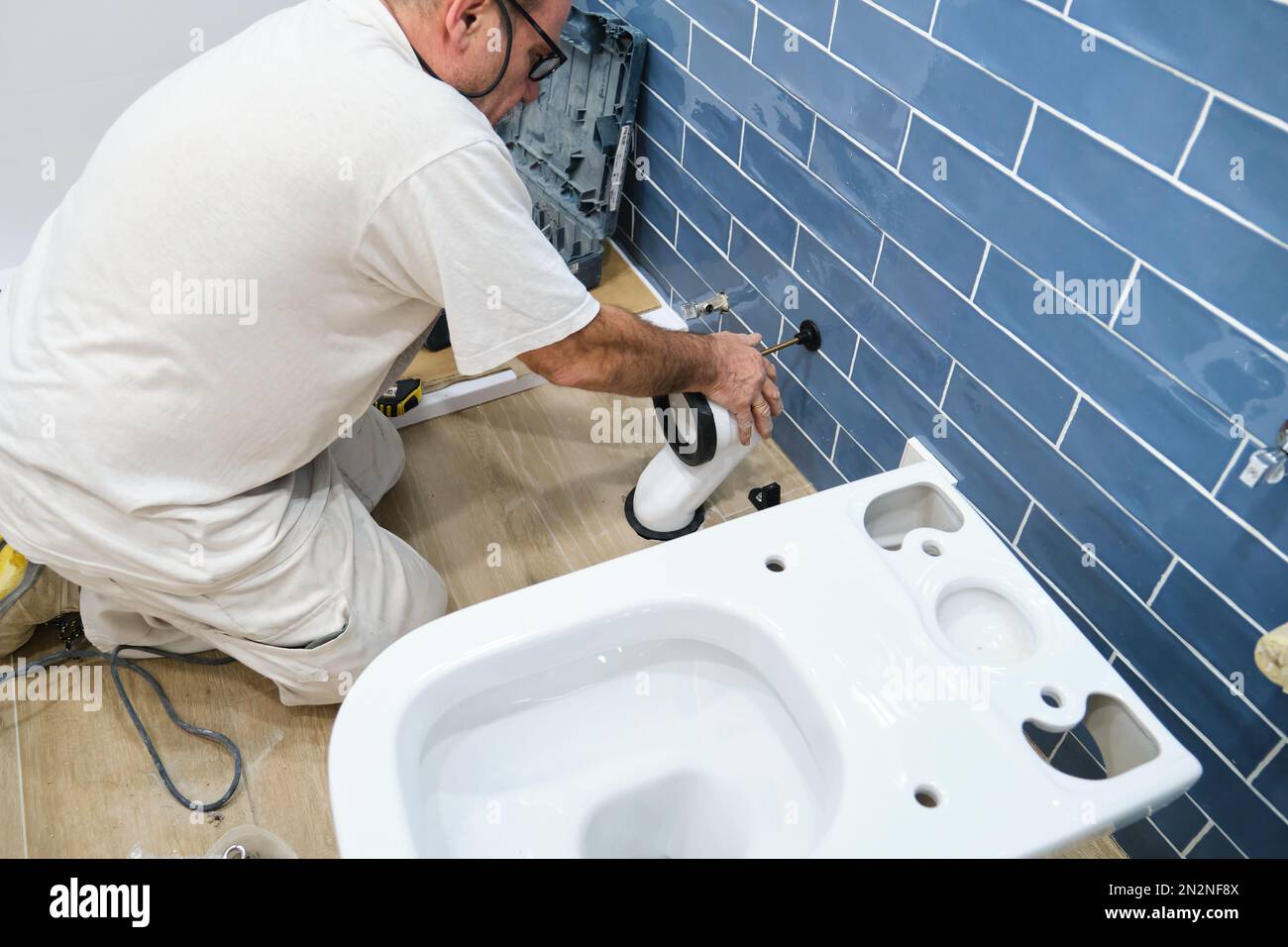 Unrecognizable senior plumber installer installing toilet drain flange