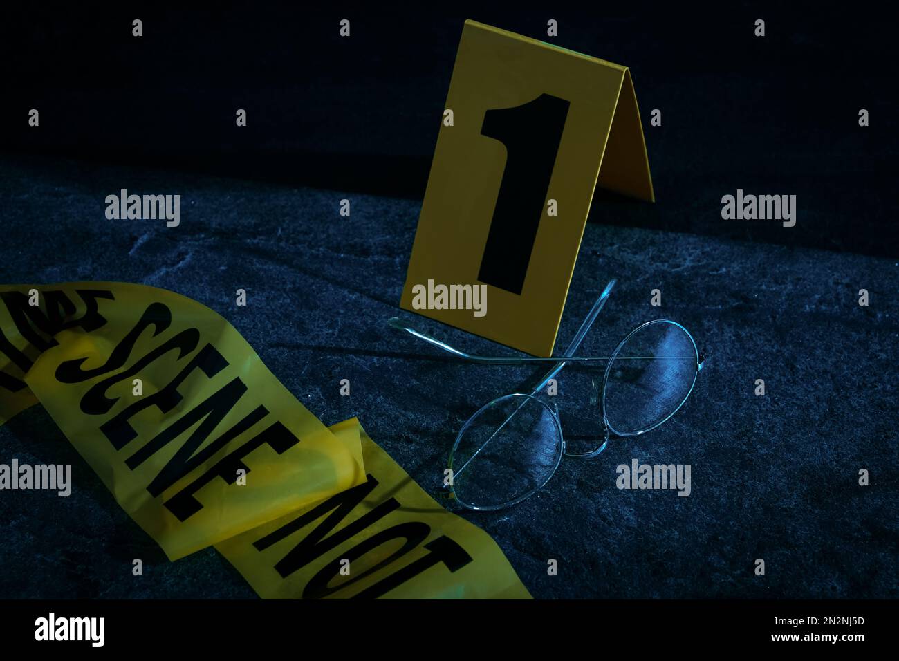 Glasses with tape and crime scene marker on stone table at night Stock ...