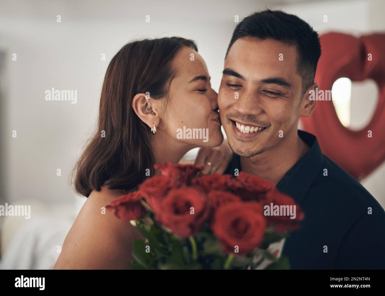 Love, flowers and valentines day with a couple kissing in their home