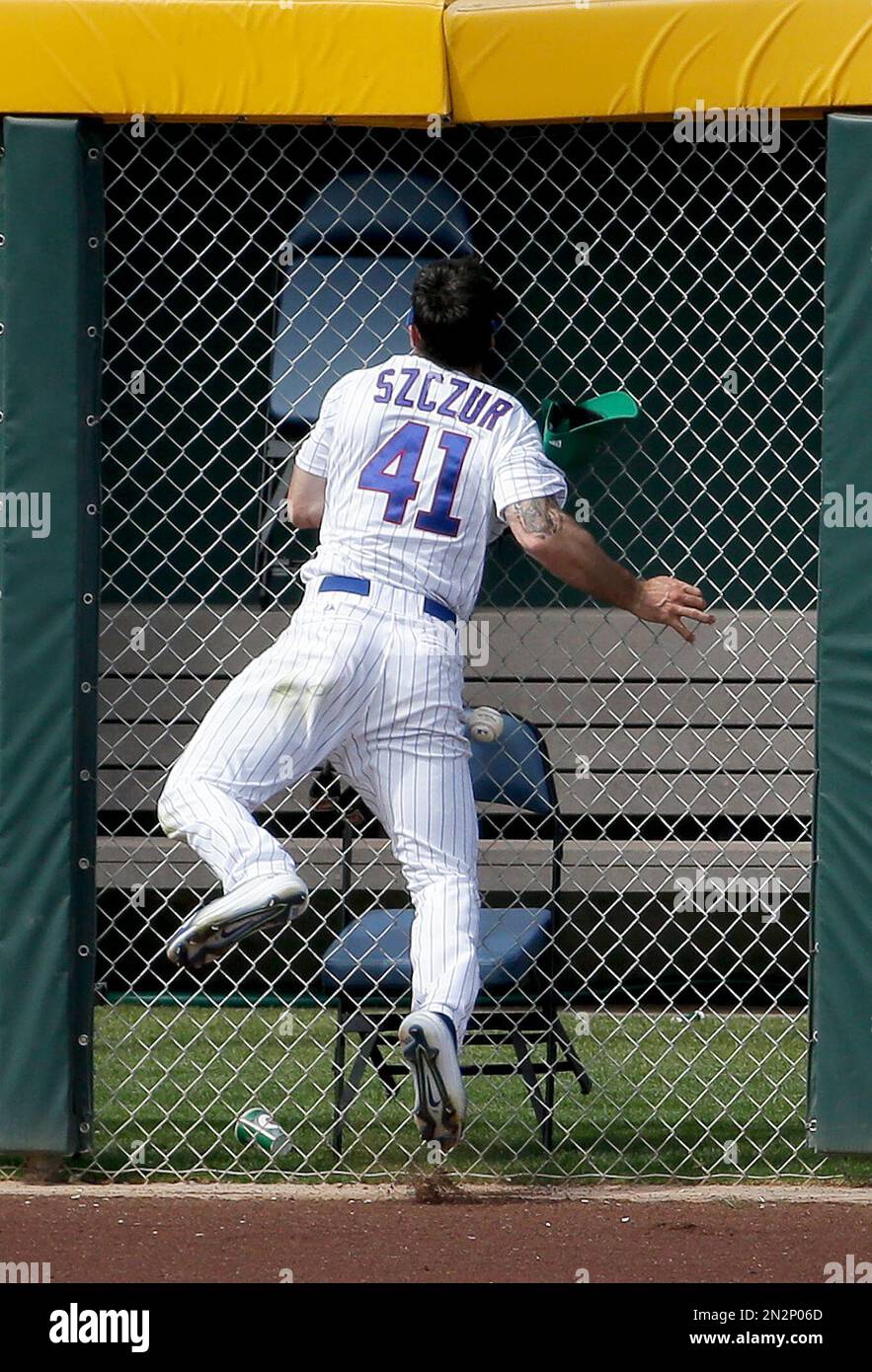 Chicago Cubs left fielder Matt Szczur collides with the bullpen fence  trying to catch a ball hit by Kansas City Royals' Alcides Escobar during  the sixth inning of a spring training baseball