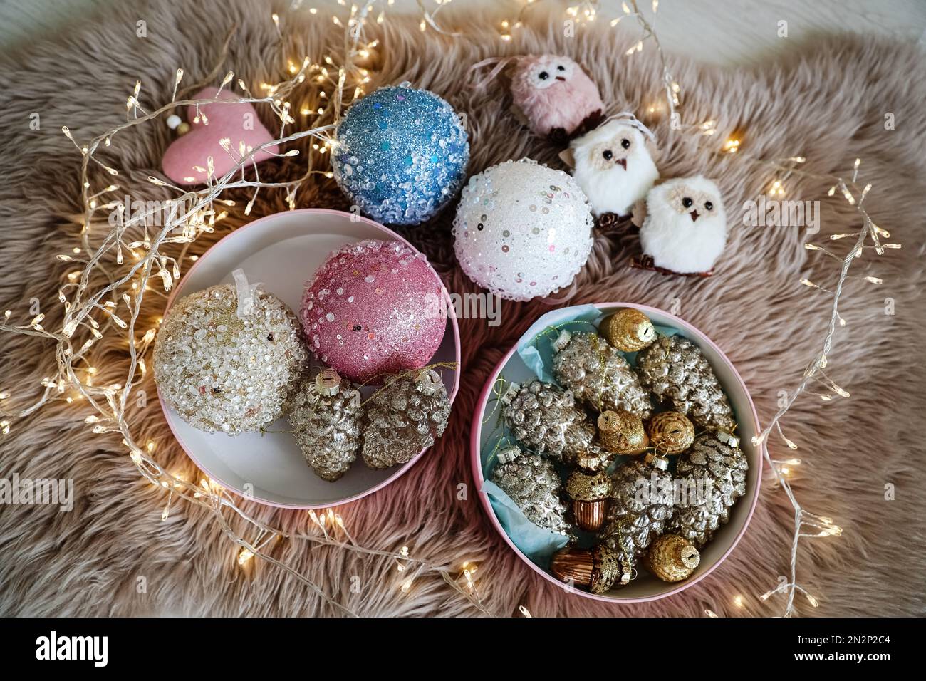 Beautiful Christmas tree baubles, toys and fairy lights on faux fur, above view Stock Photo