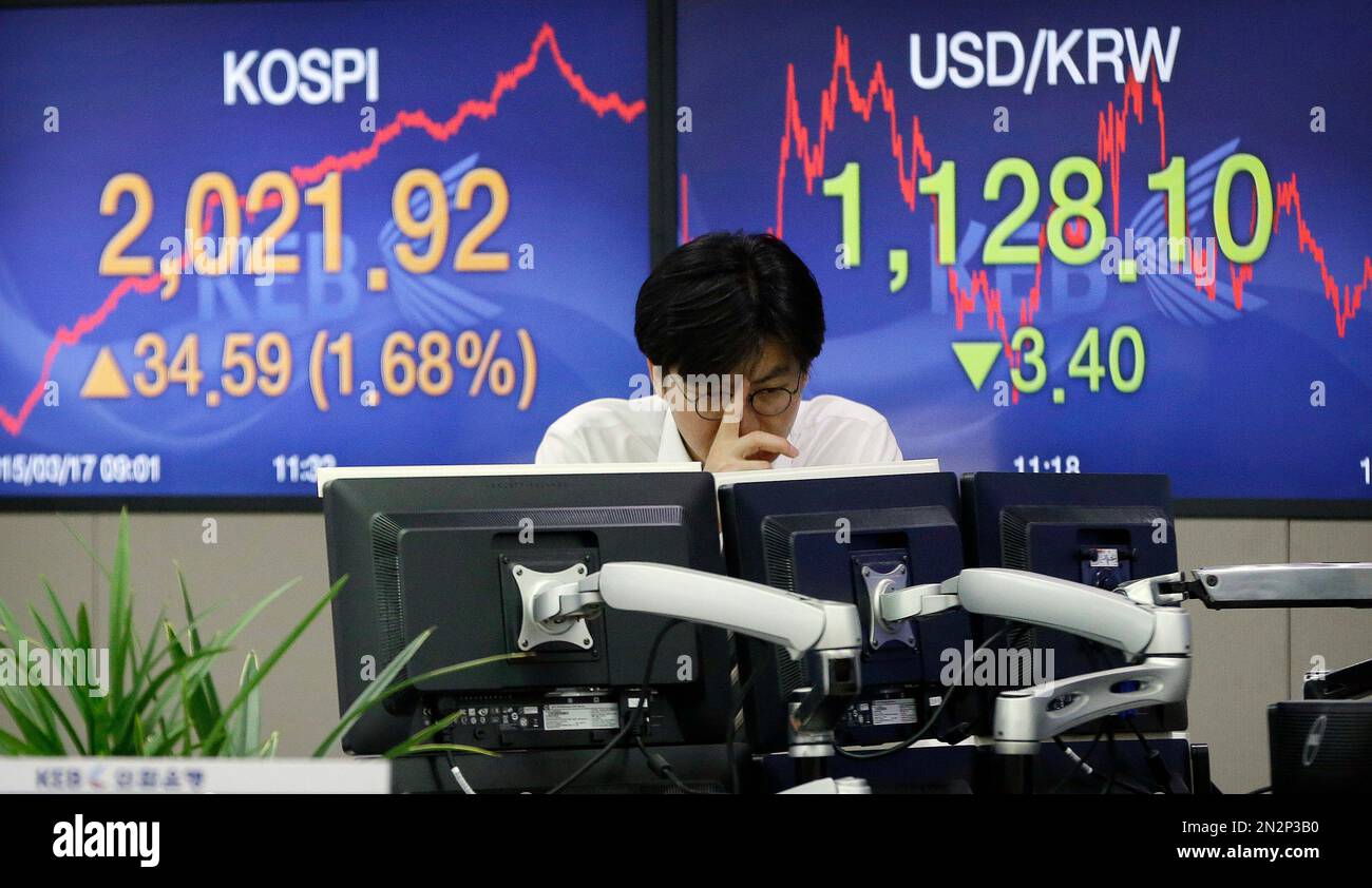 A currency trader watches monitors in front of screens showing the