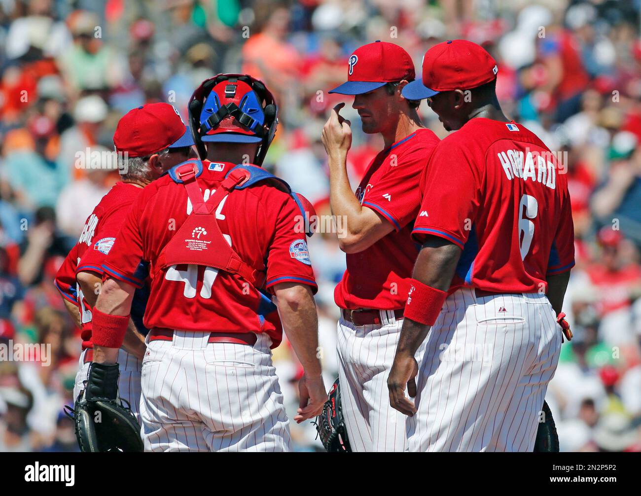Philadelphia Phillies pitching coach Bob McClure, left, talks with Phillies starting pitcher Cole Hamels, second from right, as teammates gather around in the second inning of a spring training baseball game against