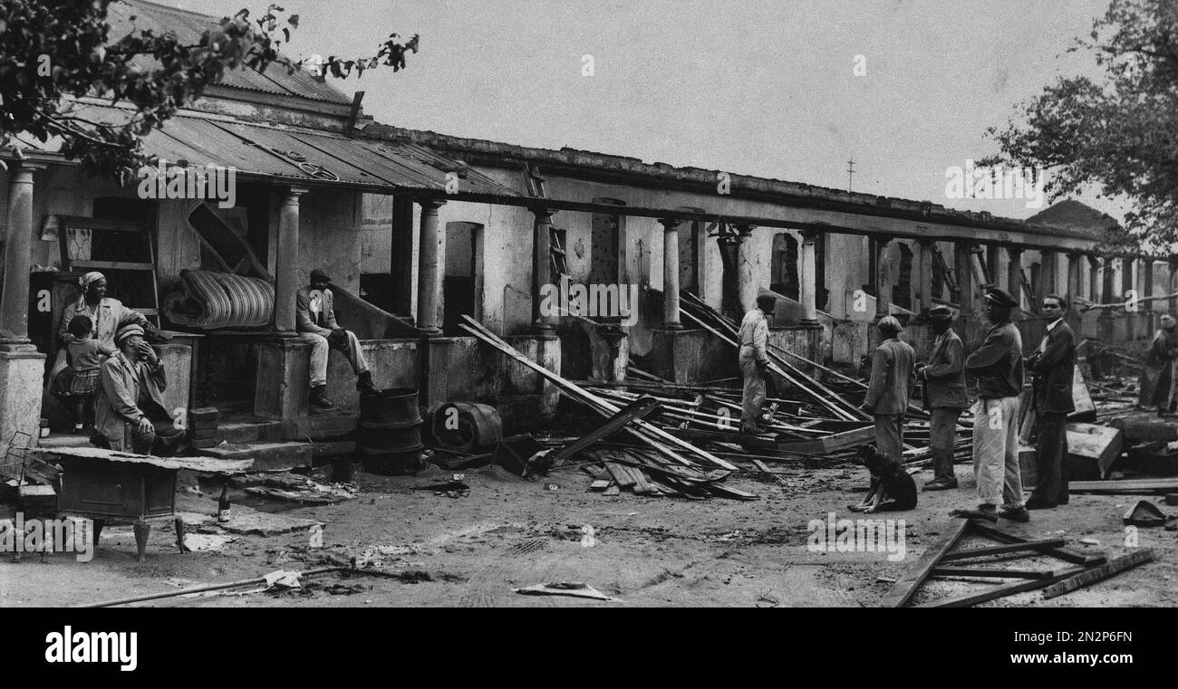 A native African family watches as demolition workers tear down a row