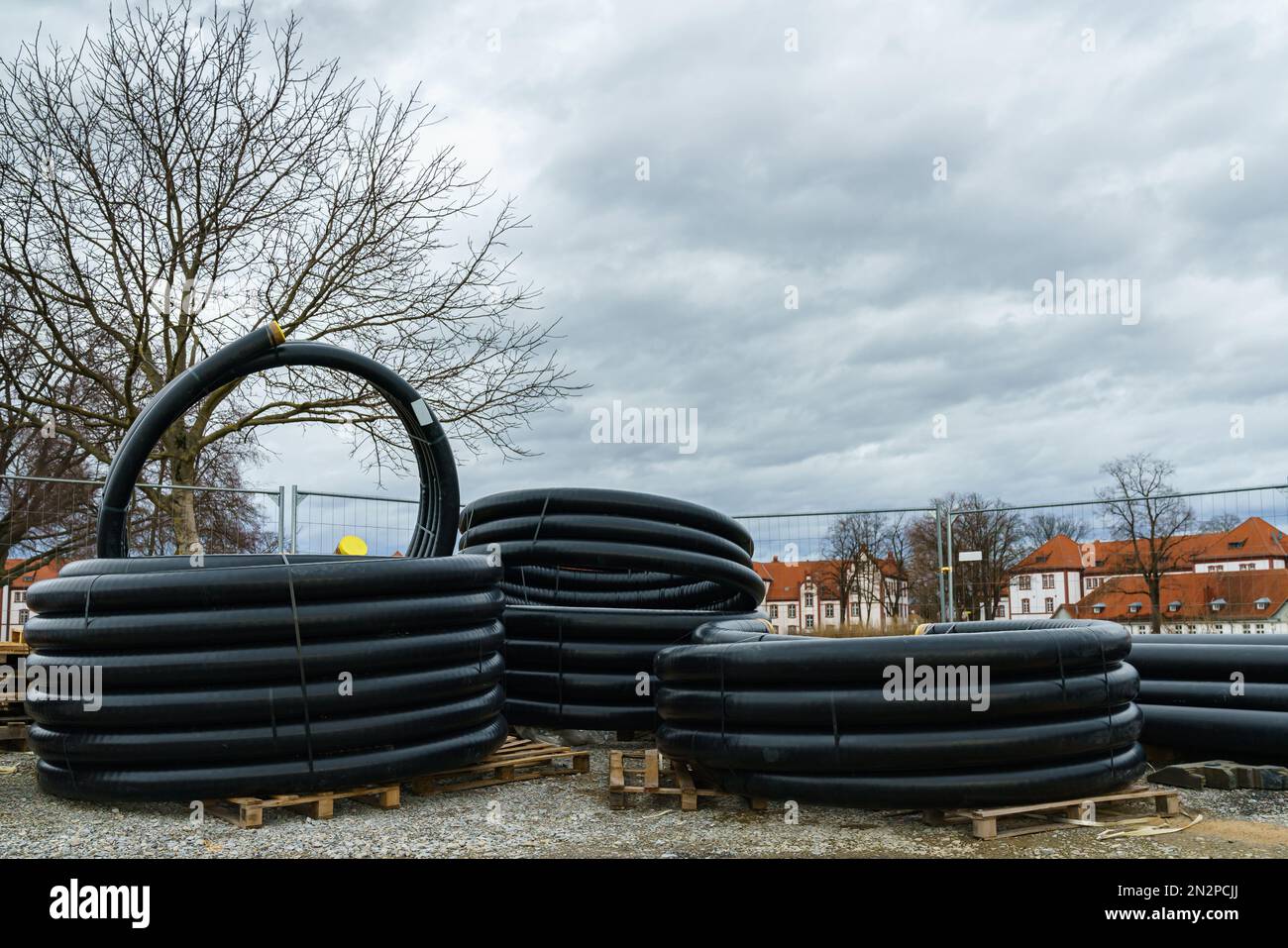 Rolls of black corrugated pipes lie on the construction site. Under ...