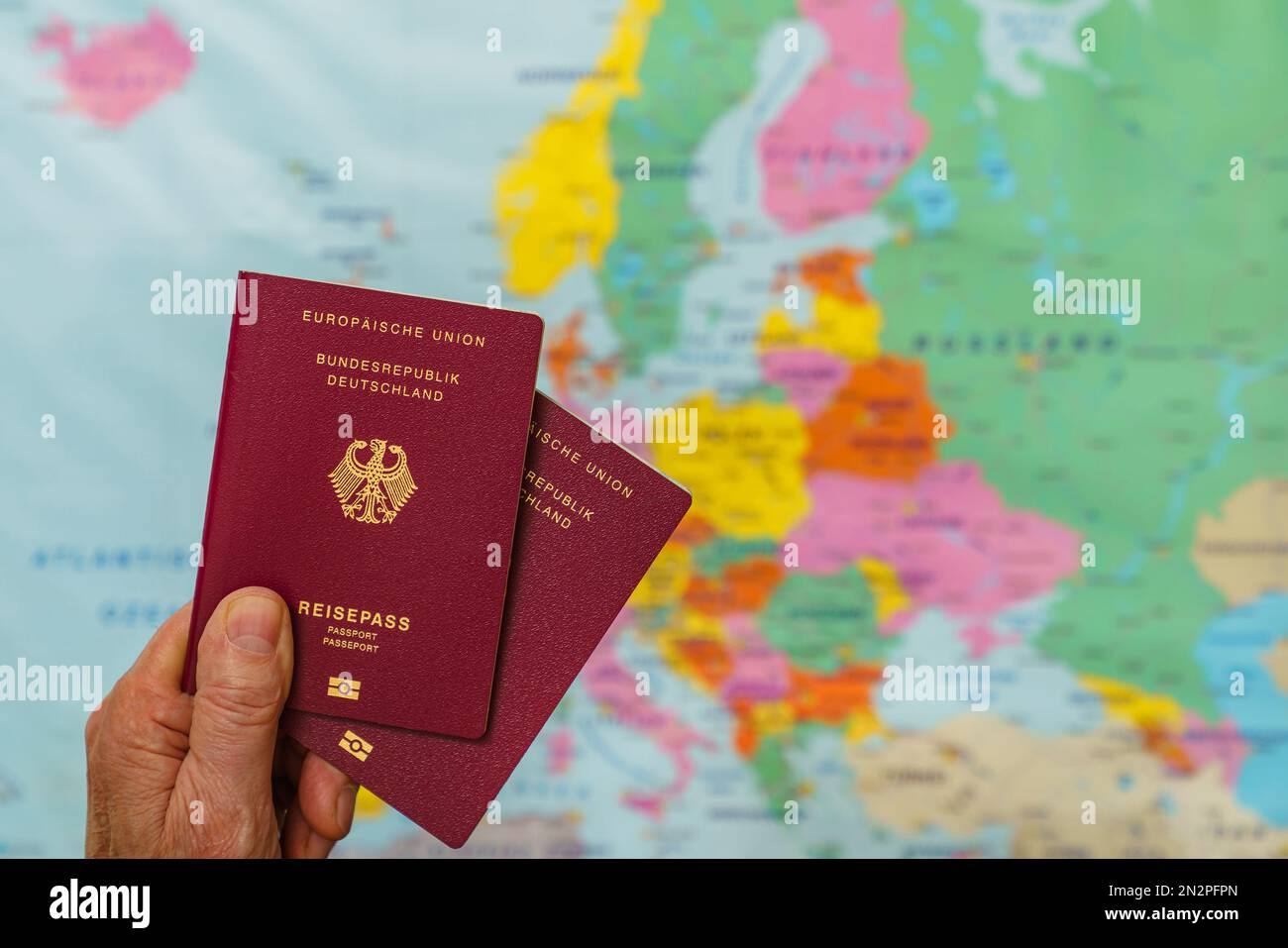Male hand with two german passports over map of europe. Close up. Stock Photo