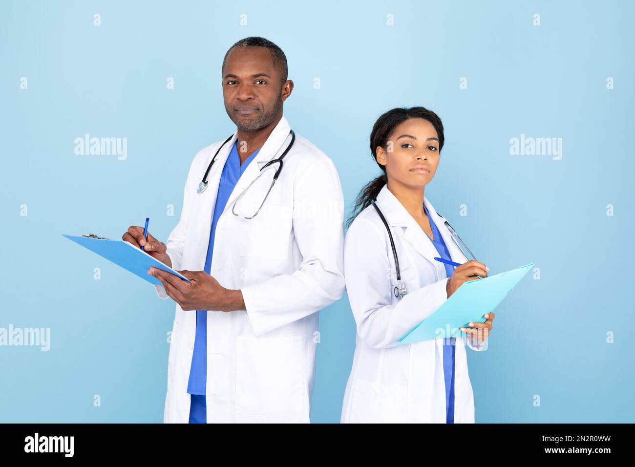 Doctors In Uniform African american male and female doctors in uniform writing notes in ...
