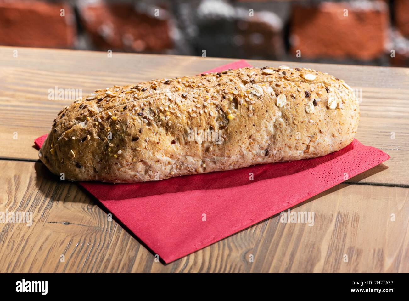 From above of loaf of fresh bread with grains placed on paper napkin on table in restaurant Stock Photo