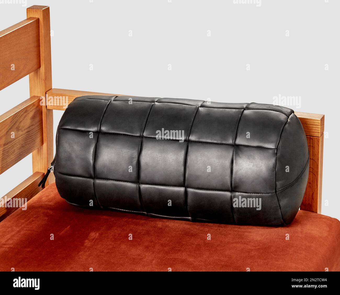 Black leather bolster cushion lying on wooden sofa Stock Photo Alamy