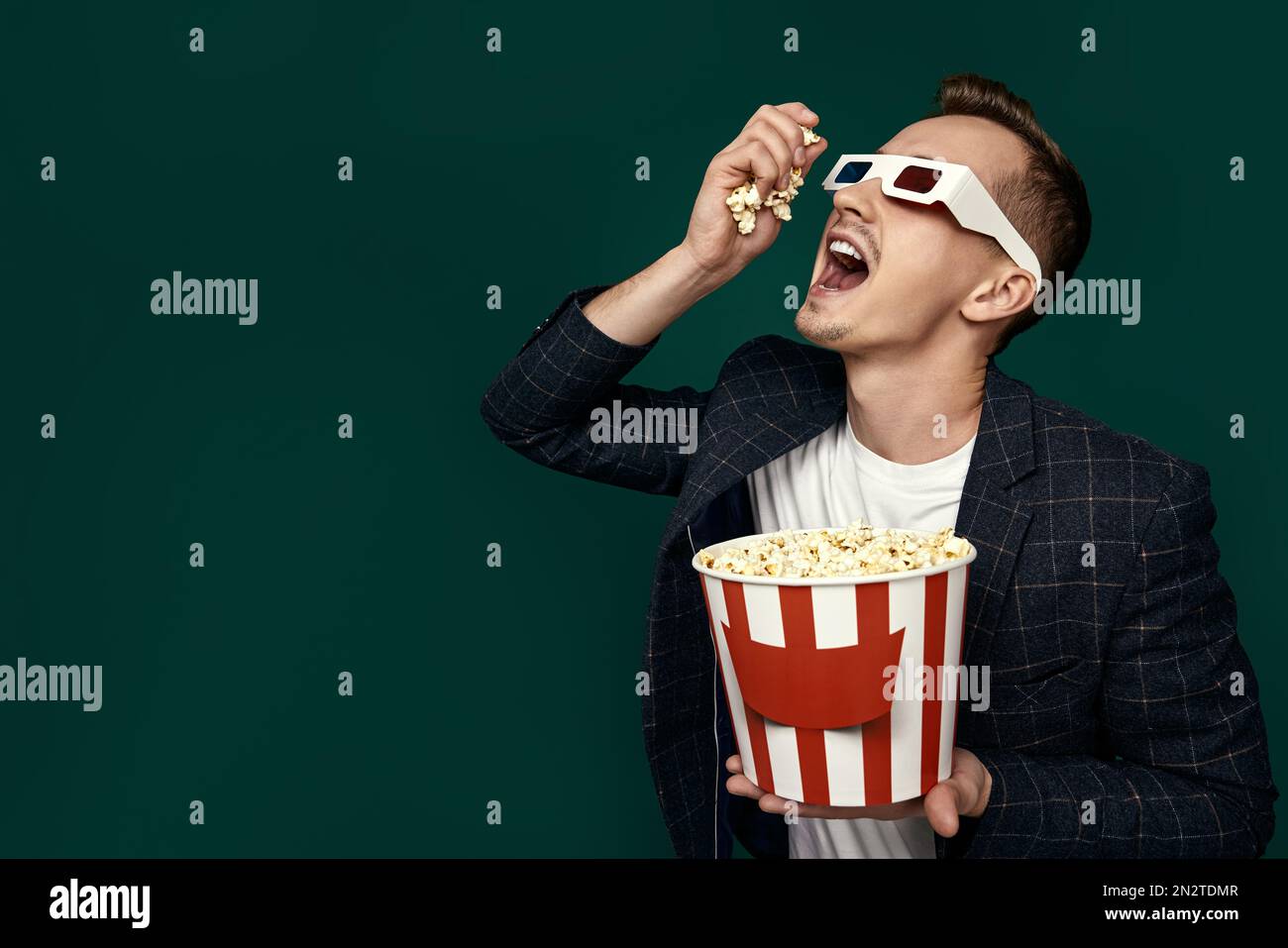 guy in 3d glasses eating popcorn on pink background Stock Photo - Alamy