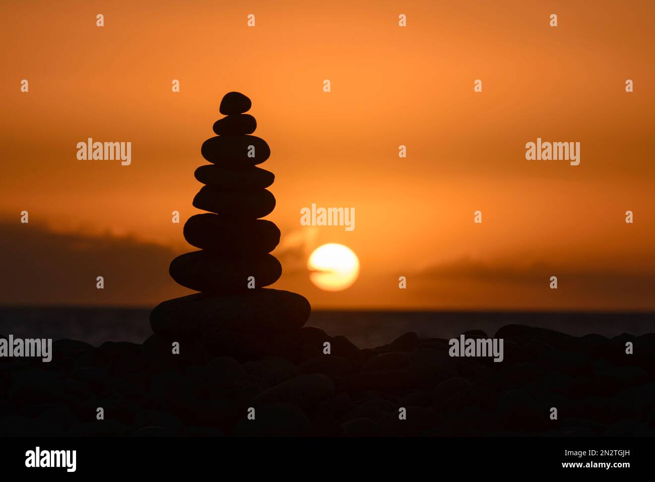 Silhouette of a stack of pebbles on beach at sunset, Playa de Arguineguin, Gran Canaria, Canary Islands, Spain Stock Photo