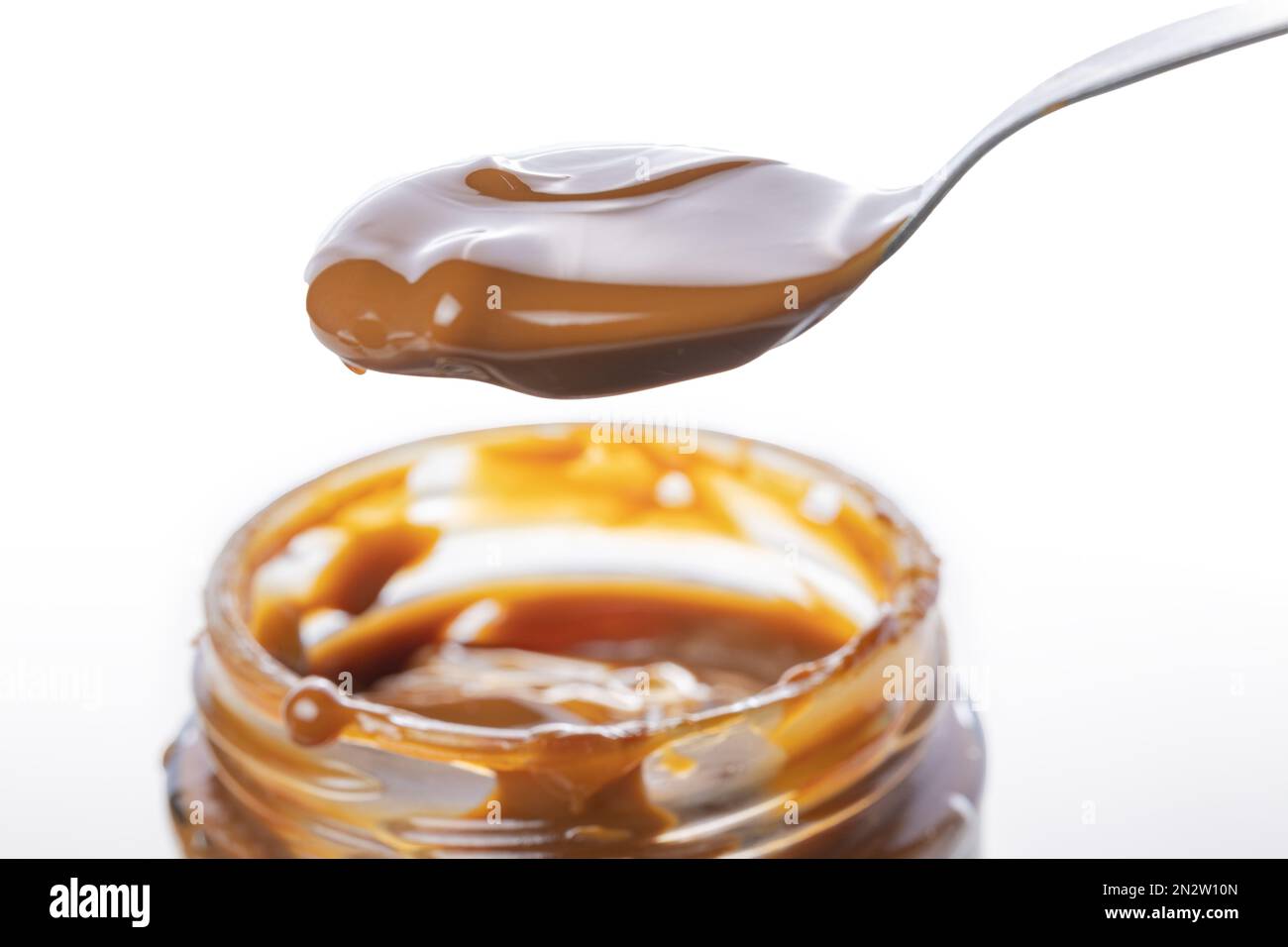 Close up of spoon scooping dulce de leche out of a jar, traditional ...