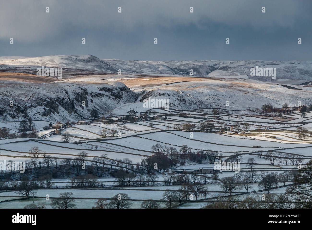Patches of sunshine drift across snow covered fells above Holwick, Upper Teesdale. Stock Photo
