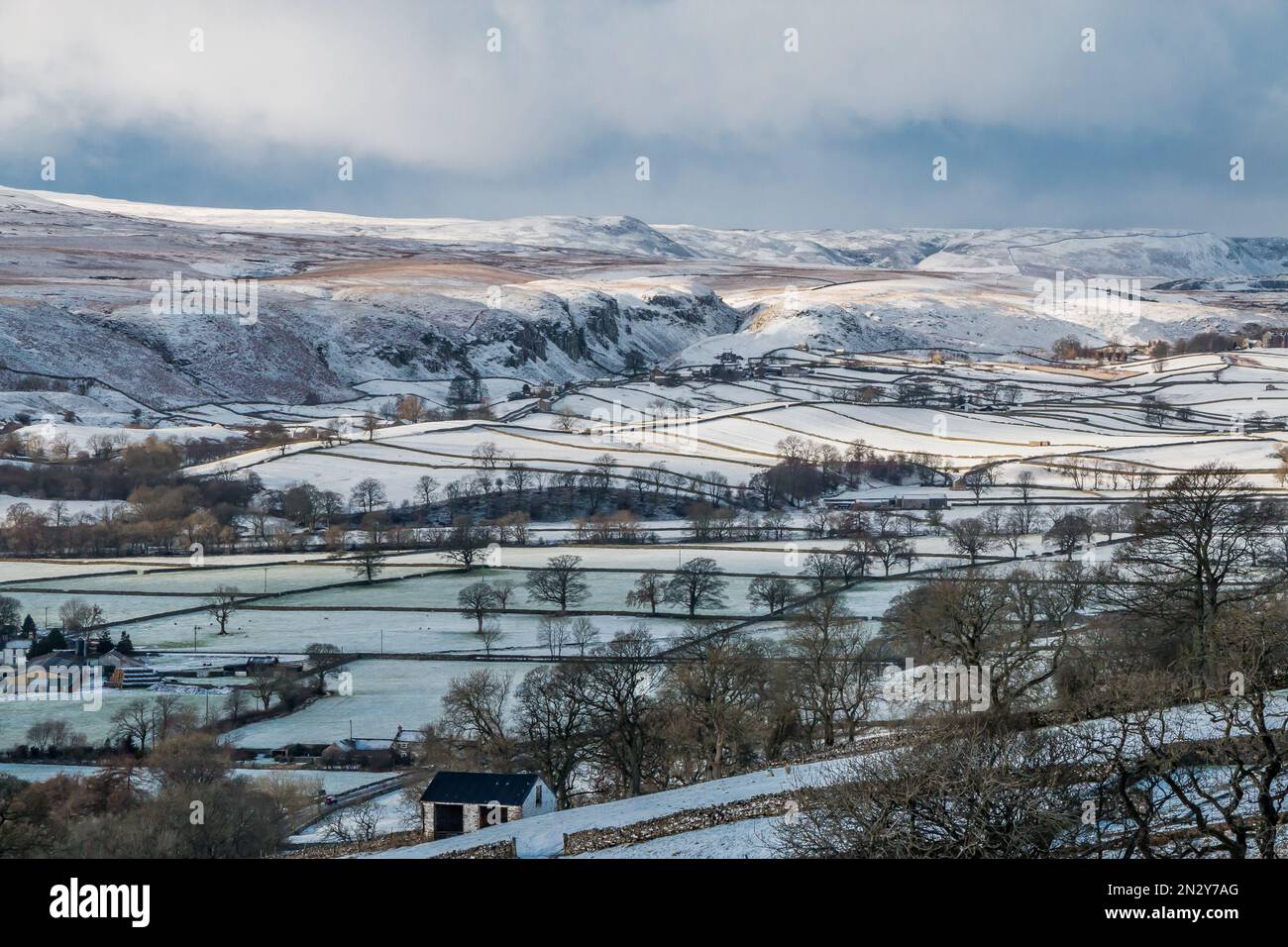 Patches of sunshine drift across snow covered fells above Holwick, Upper Teesdale. Stock Photo
