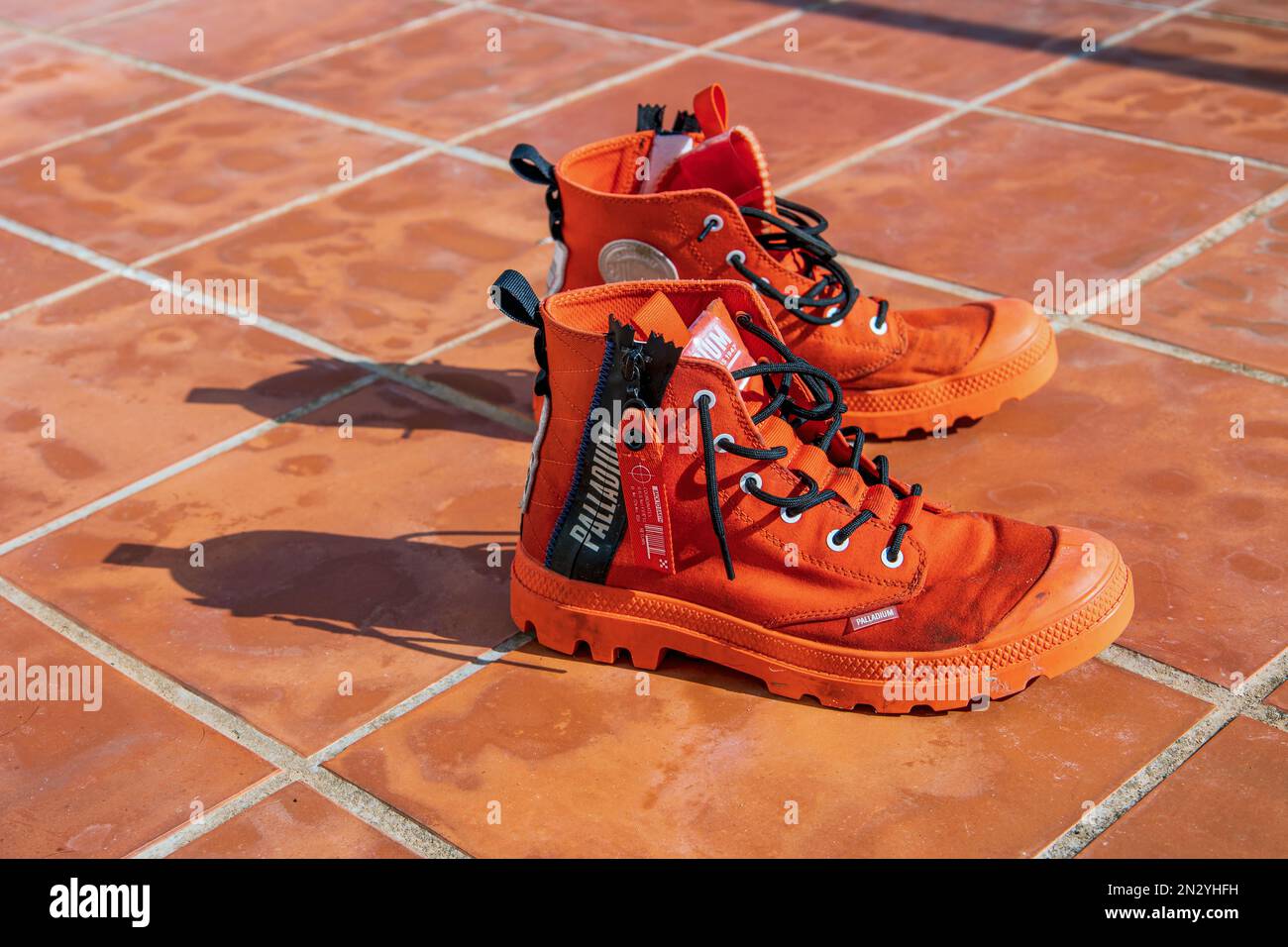 Wet orange trapper boots in the strong sun on the terracotta terrace in Catalonia. Stock Photo