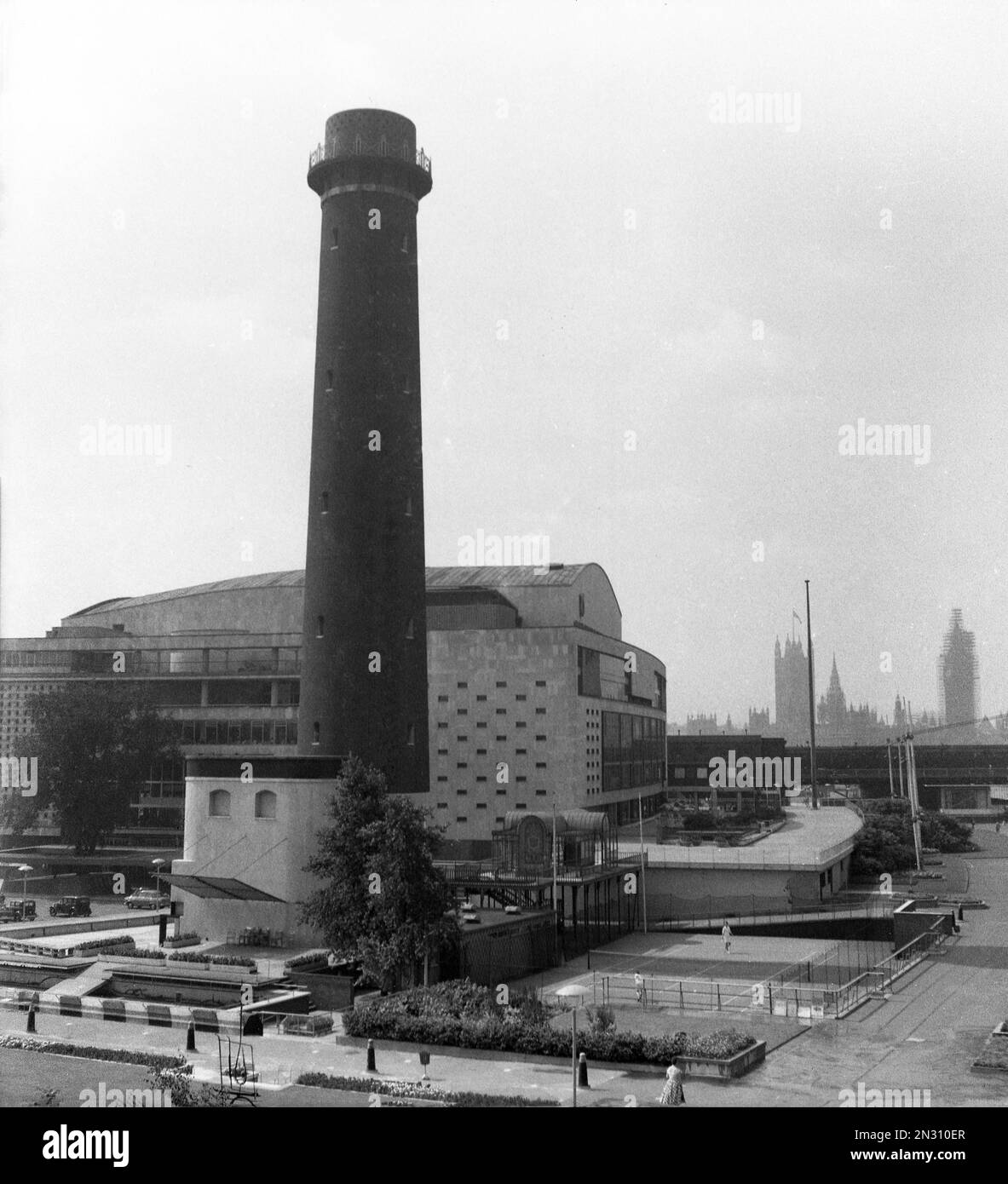 1950s, historicla, exterior view of the Shot Tower and the Royal Festival Hall, on the South Bank, Lambeth, London, England, UK. The Shot Tower at the Lambeth Lead Works, was built in 1826 and was the only existing building retained on the site for the Festival of Britain held in 1951. Designed by Sir Robert Matthew and J L Martin, the hall was built in 1949-51 as a concert hall for the Festival. Waterloo Bridge is in the distance. In 1962 the tower was demolished and the Queen Elizabeth Hall opened in 1967. Stock Photo