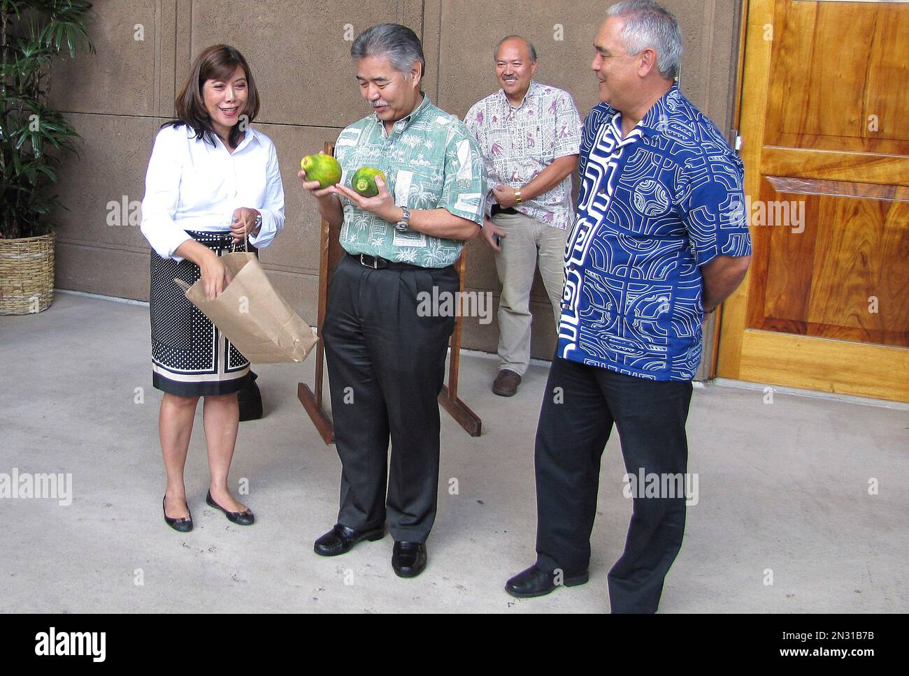 Hawaii Gov. David Ige, center, accepts modified papayas