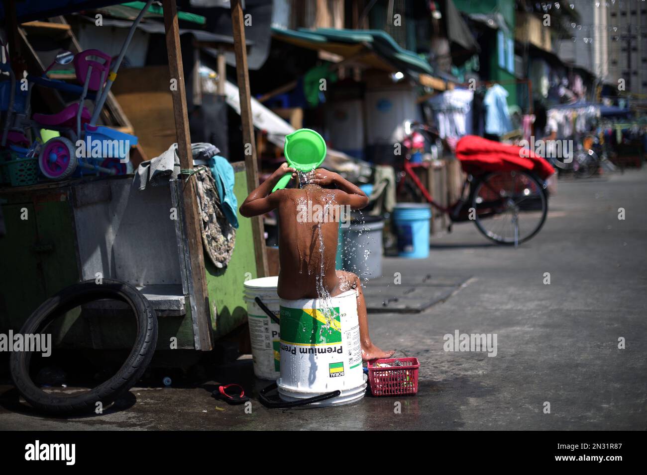 A Filipino boy takes a bath outside his house in Manila, Philippines on ...