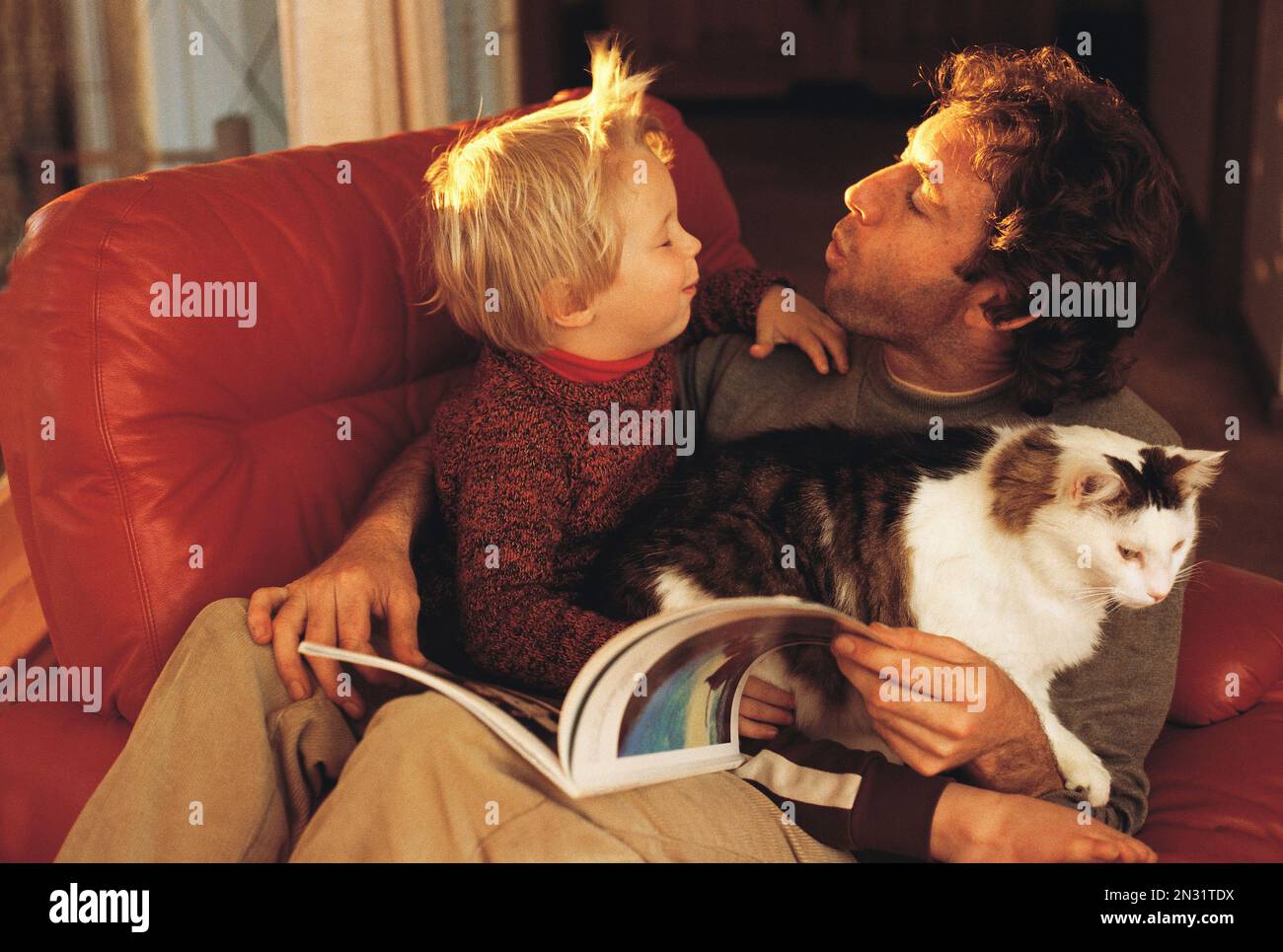 Man and boy indoors at home with pet cat. Stock Photo