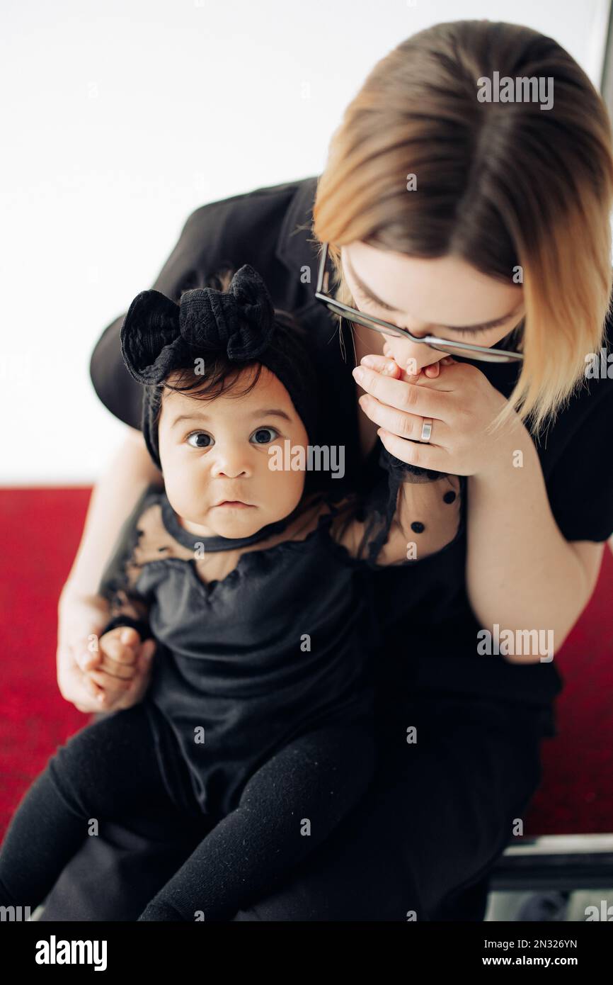 Happy caucasian woman sits and embraces her baby daughter from