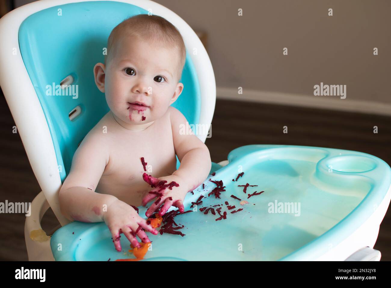 Baby eating solid foods in a high chair. Babyled weaning. Baby eating