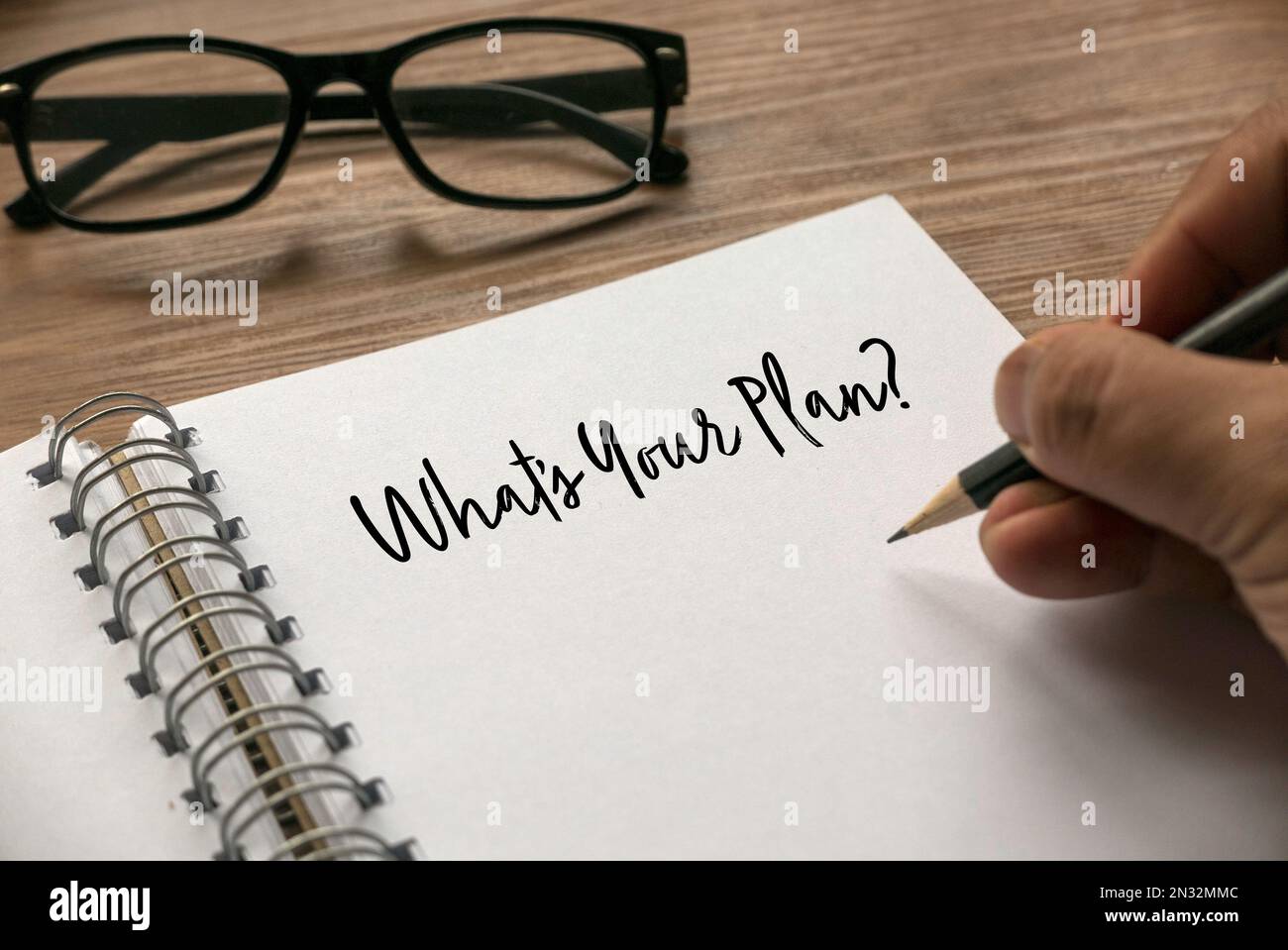A hand writing a question What's Your Plan? on a notebook. Stock Photo