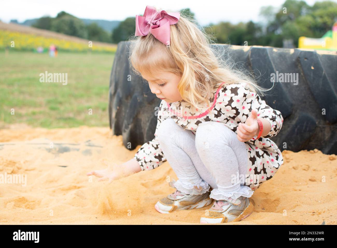 Caucasian blond little toddler girl playing in the sand. Sensory play Stock Photo