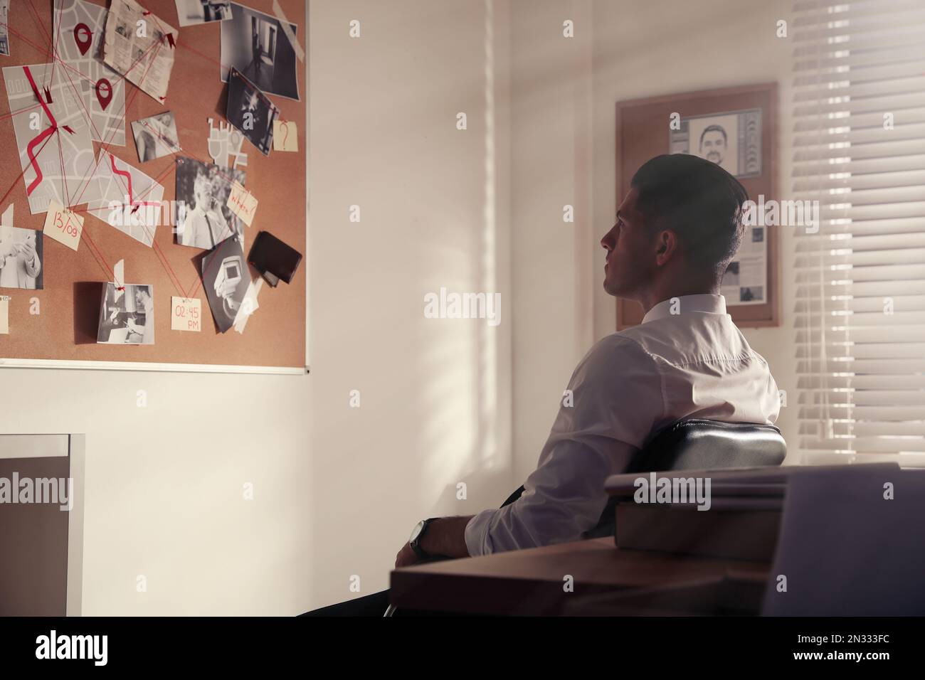 Detective looking at evidence board in office Stock Photo
