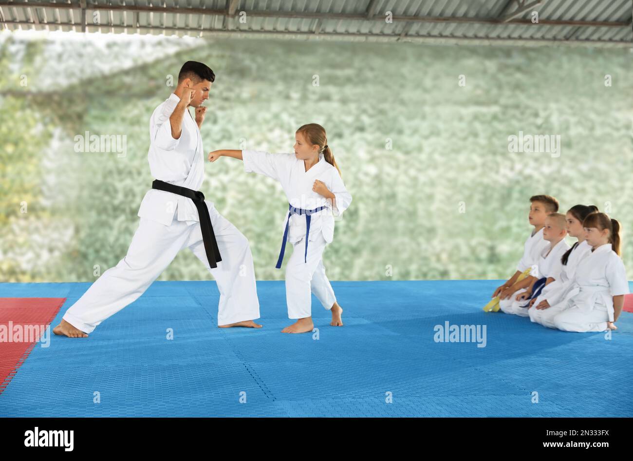 Girl practicing karate with coach on tatami outdoors Stock Photo