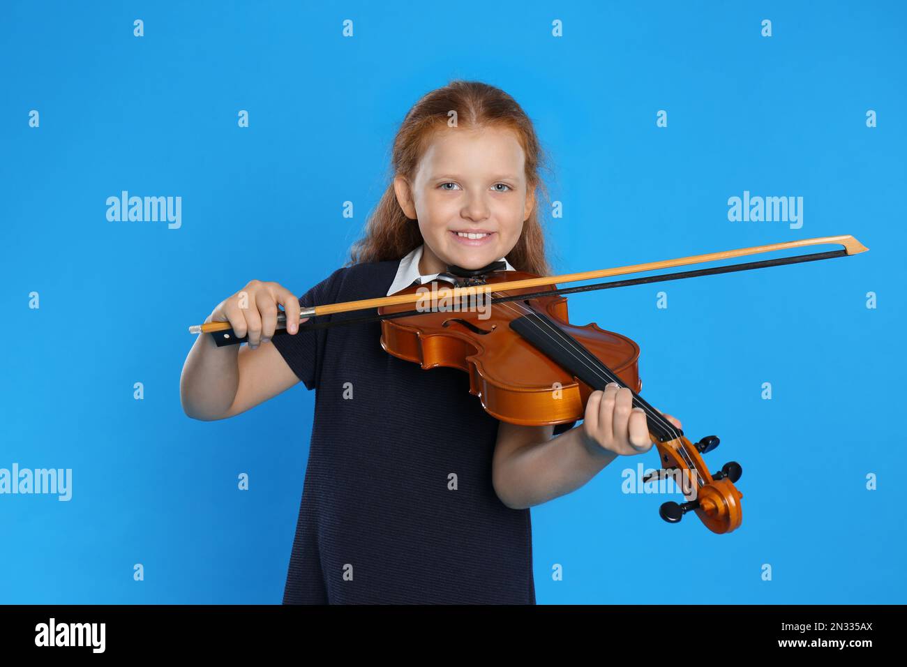 Preteen girl playing violin on light blue background Stock Photo - Alamy