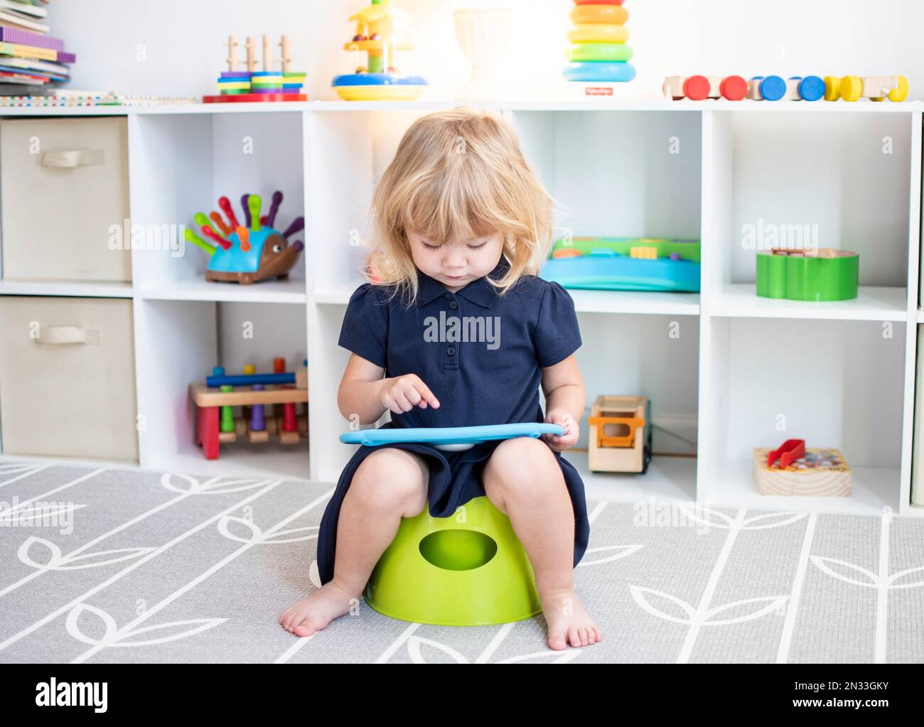 Caucasian toddler sitting on a potty with the tablet Stock Photo