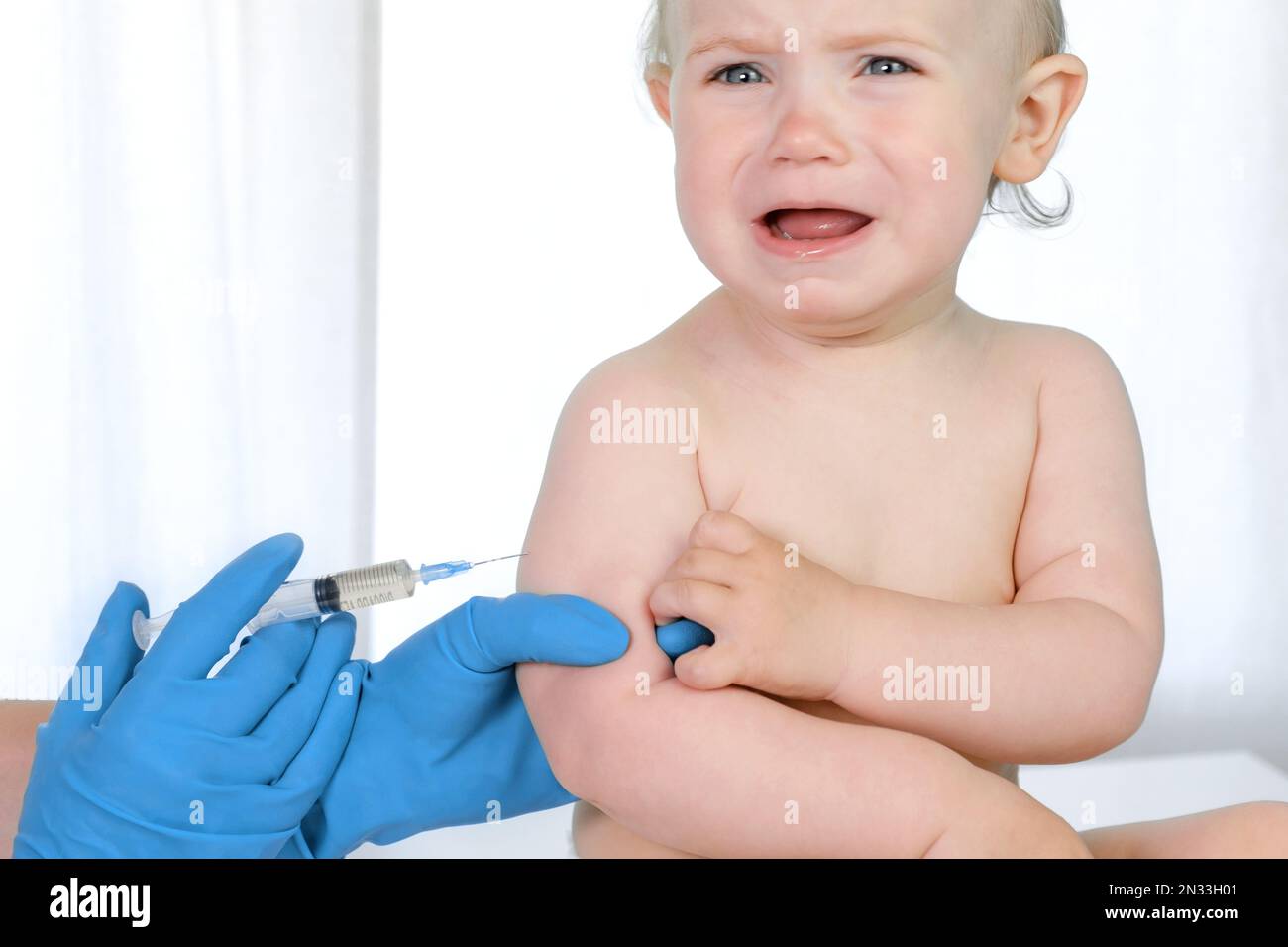 Doctor vaccinating crying baby in clinic. Little baby get an injection. Pediatrician vaccinating newborn baby. Vaccine for infant child. Child's Immun Stock Photo