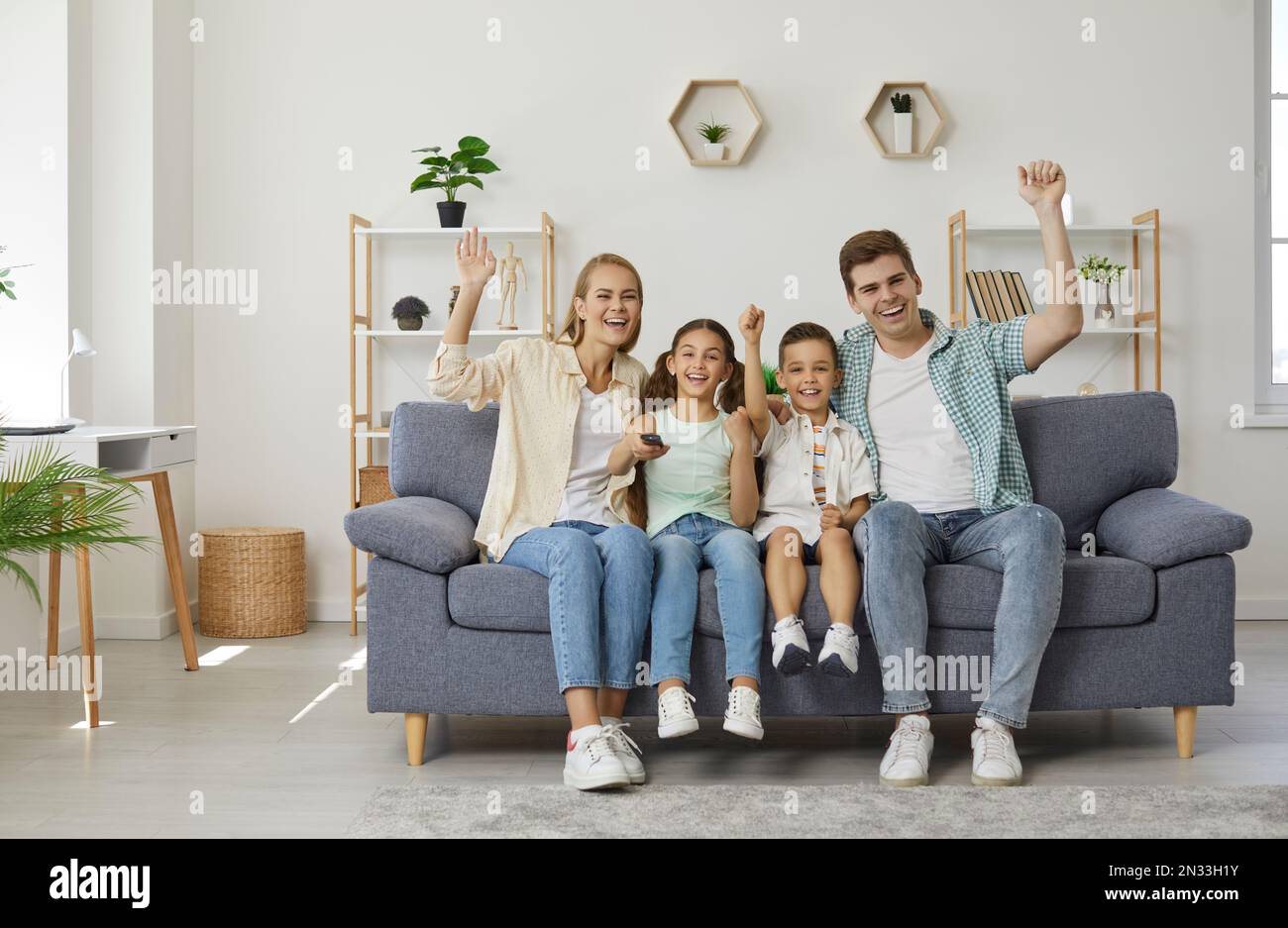Happy family on couch is watching sport game on TV and and they are happy of winning of their team. Stock Photo