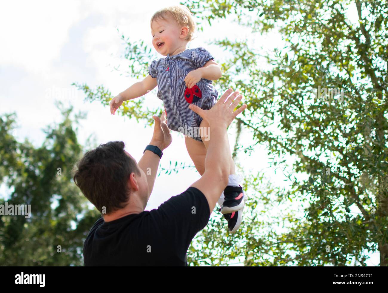 Father throws happy baby daughter up in the air. Fatherhood. Happy