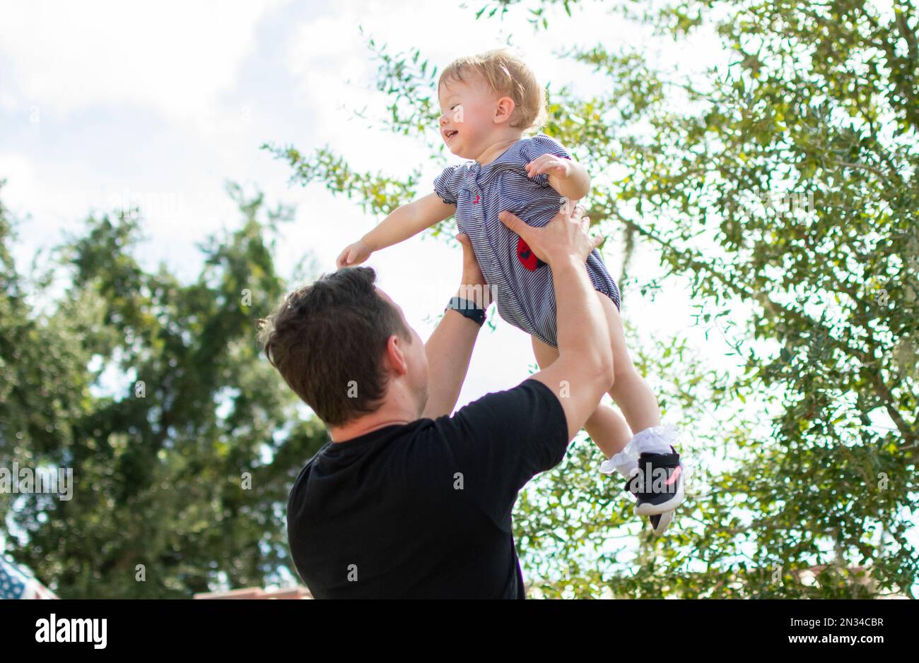 Father throws happy baby daughter up in the air. Fatherhood. Happy