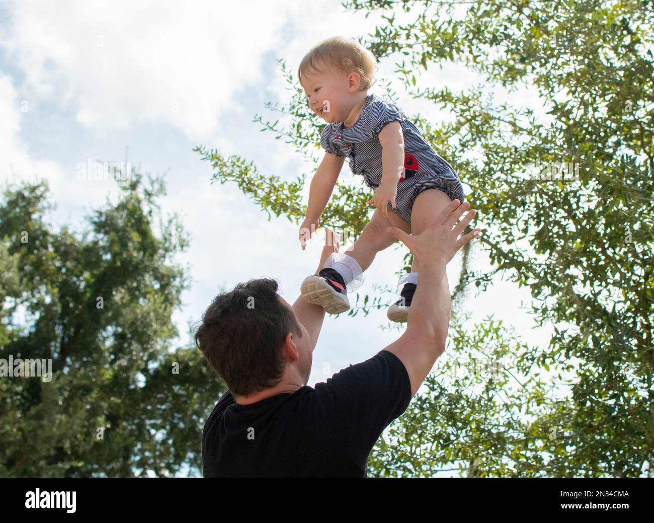 Father throws happy baby daughter up in the air. Fatherhood. Happy
