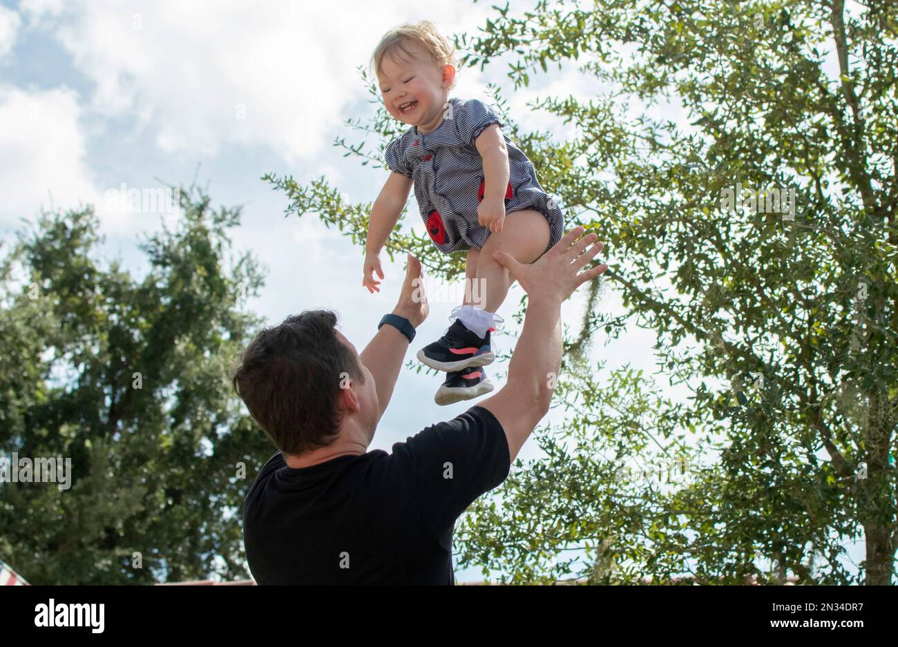 Father throws happy baby daughter up in the air. Fatherhood. Happy