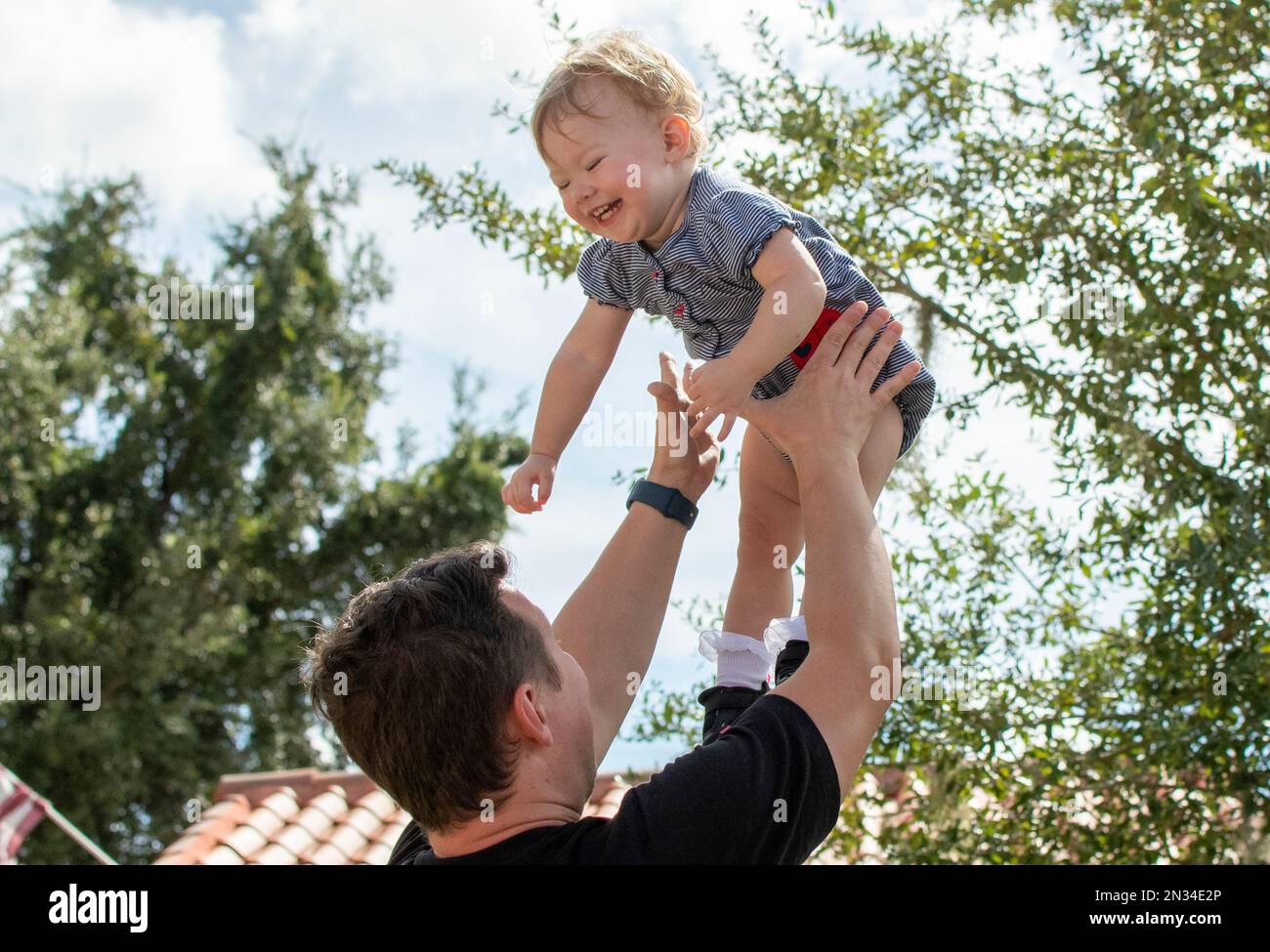 Father throws happy baby daughter up in the air. Fatherhood. Happy