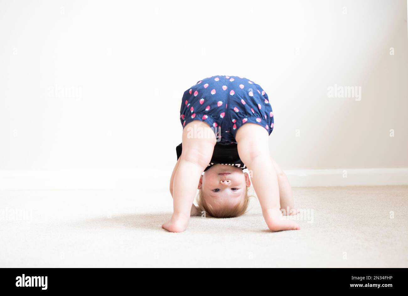 Happy cute caucasian one year old child standing upside down Stock Photo