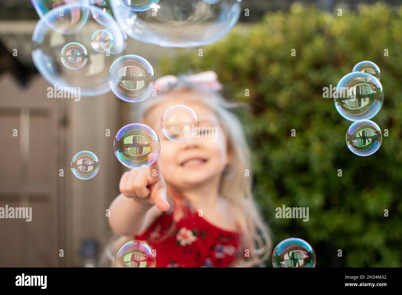 Little girl playing with bubbles. Happy child popping bubbles Stock
