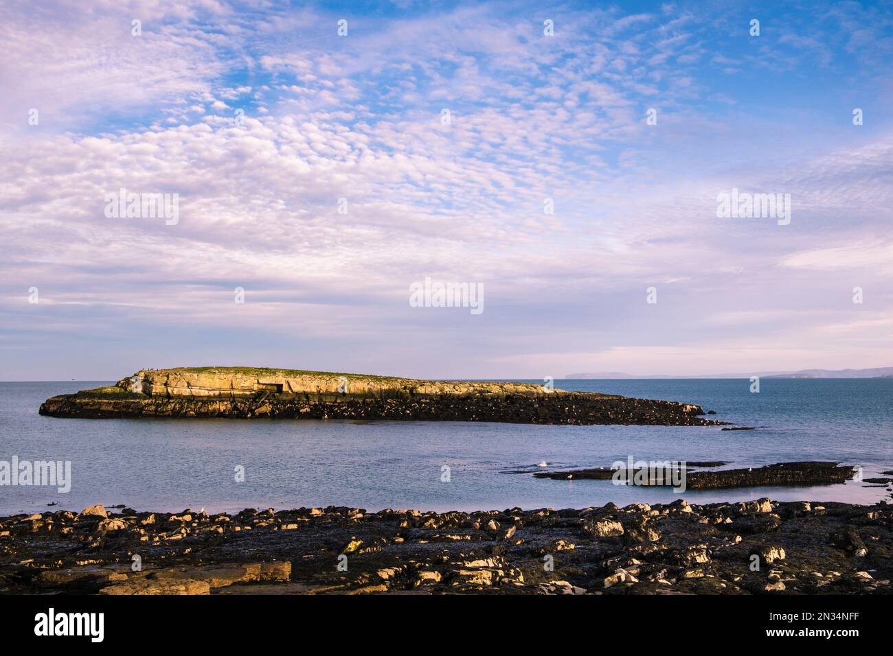 View across rocky coast to Ynys Moelfre island across Y Swnt at low tide. Moelfre, Isle of Anglesey, Wales, UK, Britain Stock Photo