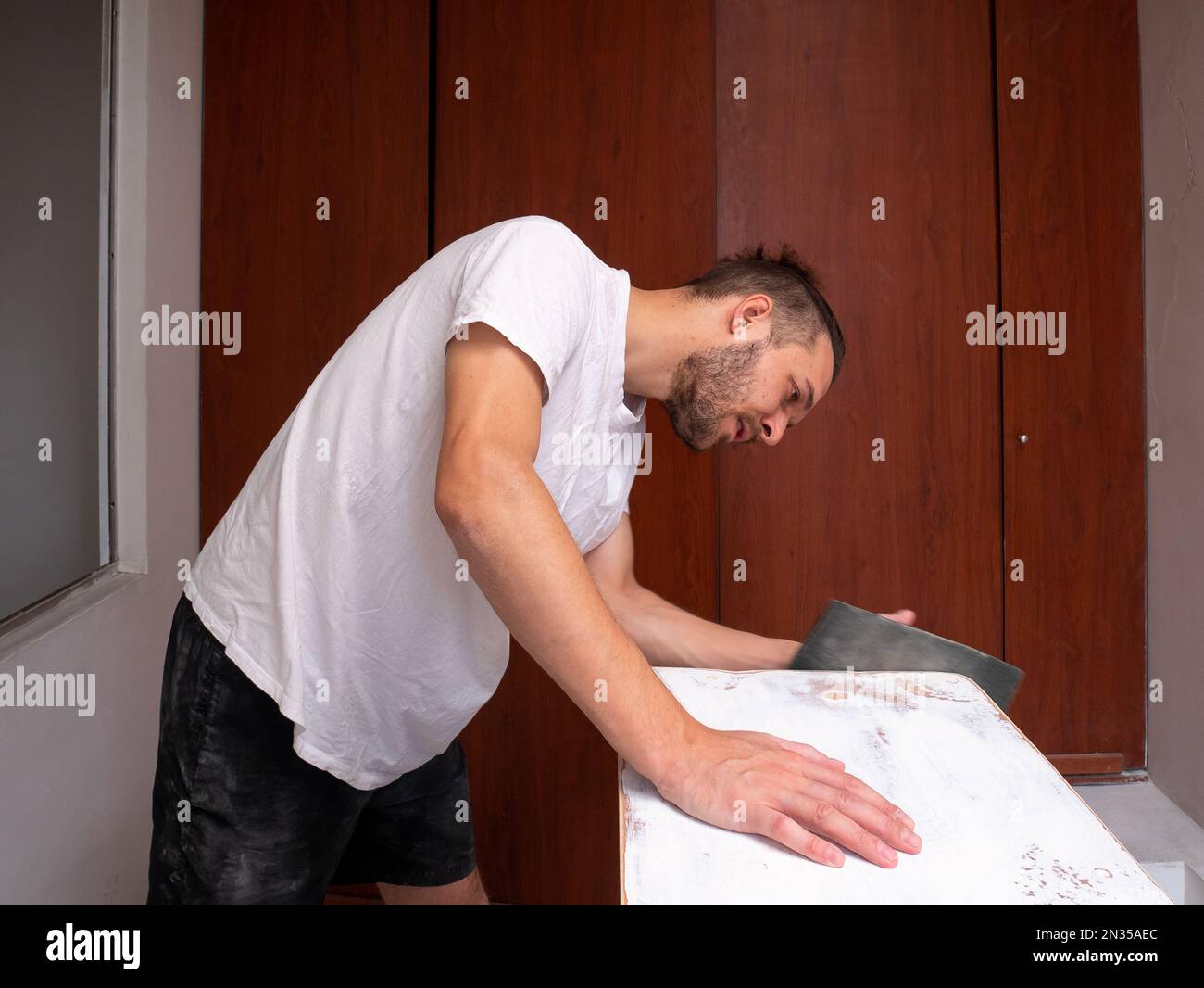 White Man Sands a White Wooden Table Using Sandpaper Stock Photo Alamy