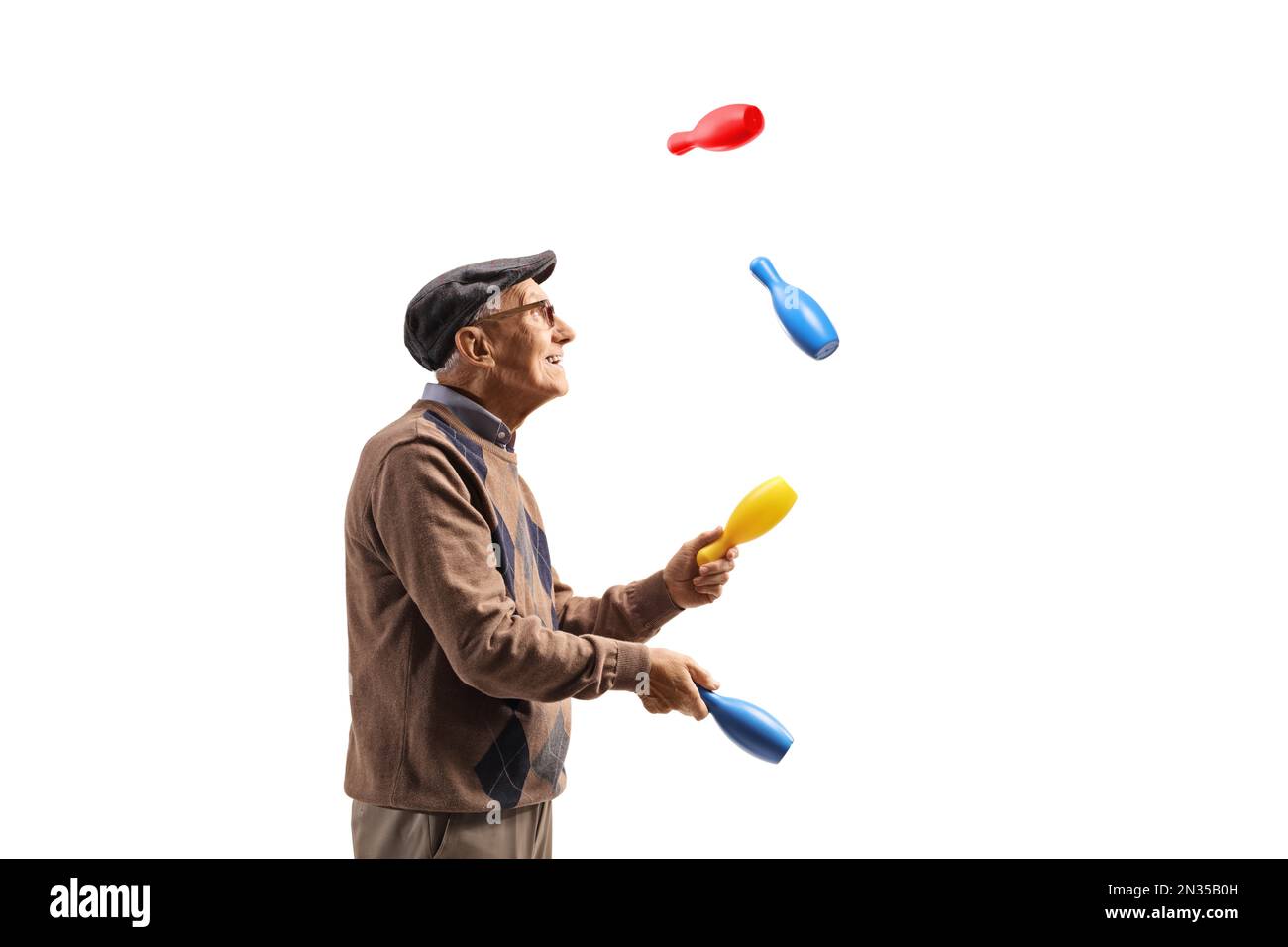 Profile shot of an elderly man juggling with clubs isolated on white background Stock Photo