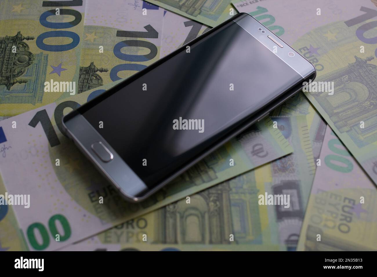 smartphone lies on 100 euro banknotes Stock Photo