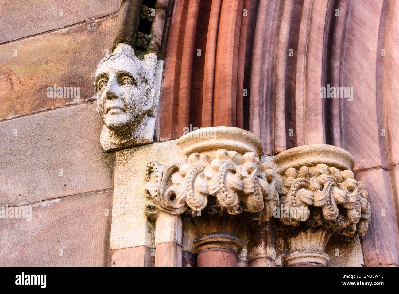 Ornately carved stone head and face on the outside of a church entrance. Stock Photo