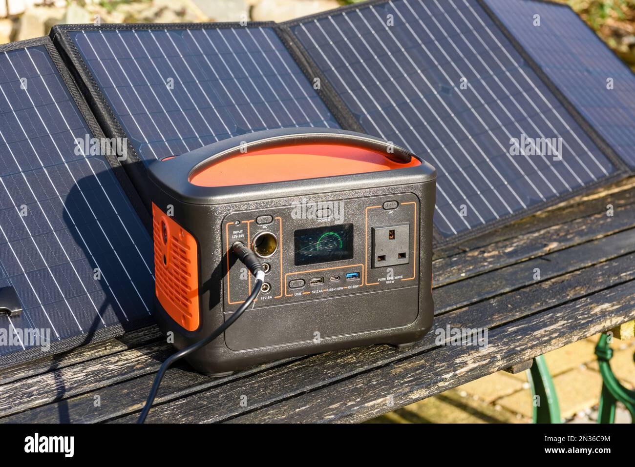 Solar generator battery pack being charged by panels in the sun Stock Photo