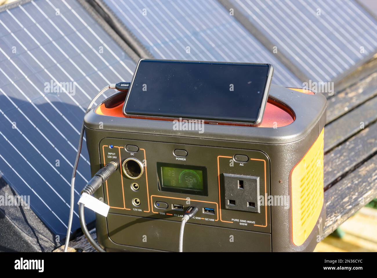 Mobile phone being charged by a solar generator battery pack with solar panels in the sun Stock Photo