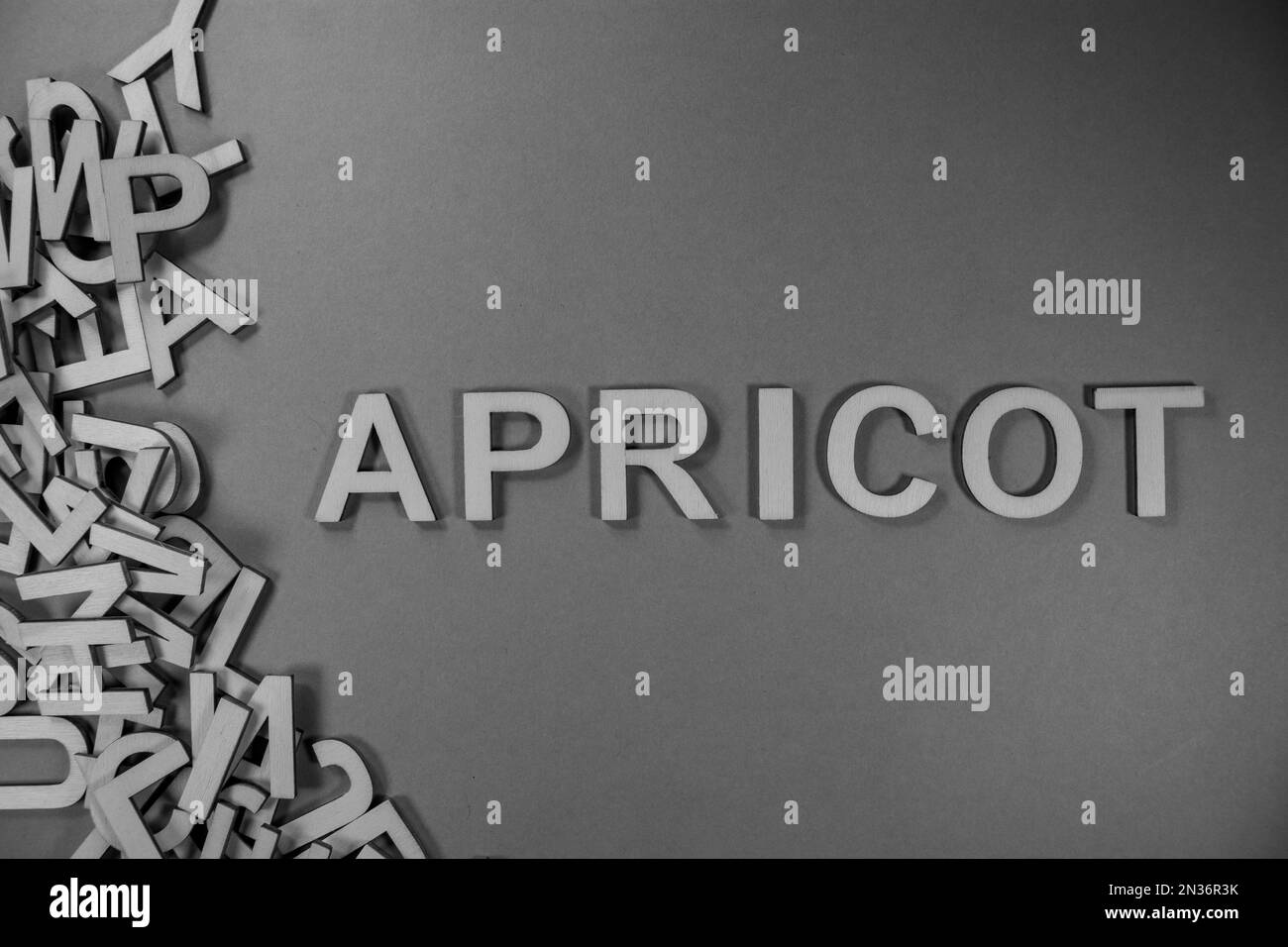 APRICOT fruit in wooden English language capital letters spilling from a pile of letters in black and white Stock Photo