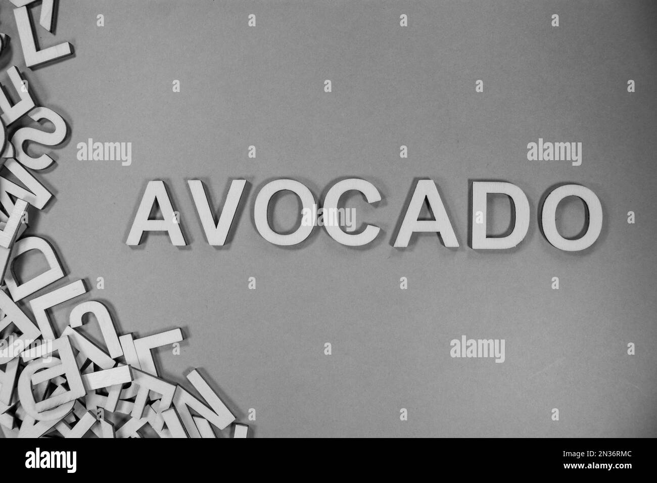 AVOCADO in wooden English language capital letters spilling from a pile of letters in black and white Stock Photo